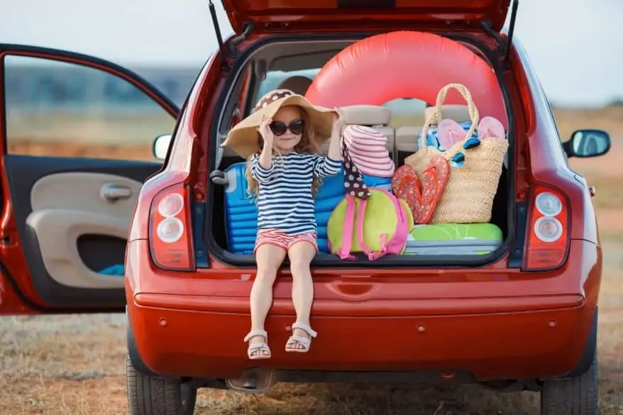 little girls sitting in the back of car at the beach