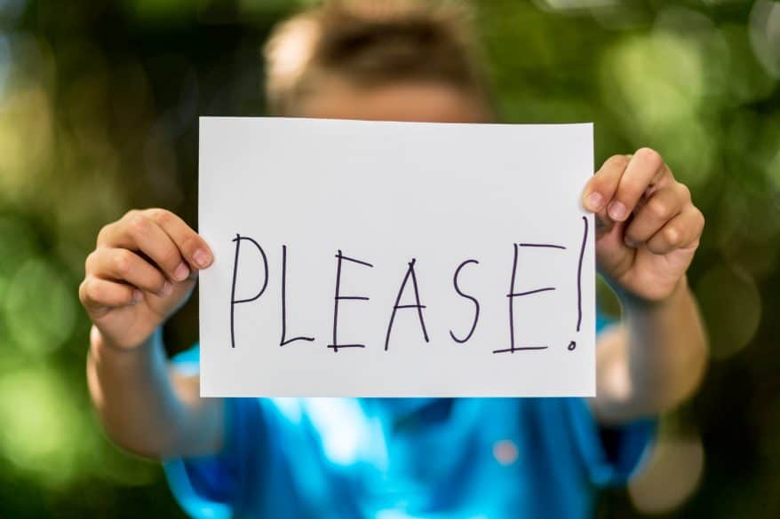 boy holding a sign with the word please