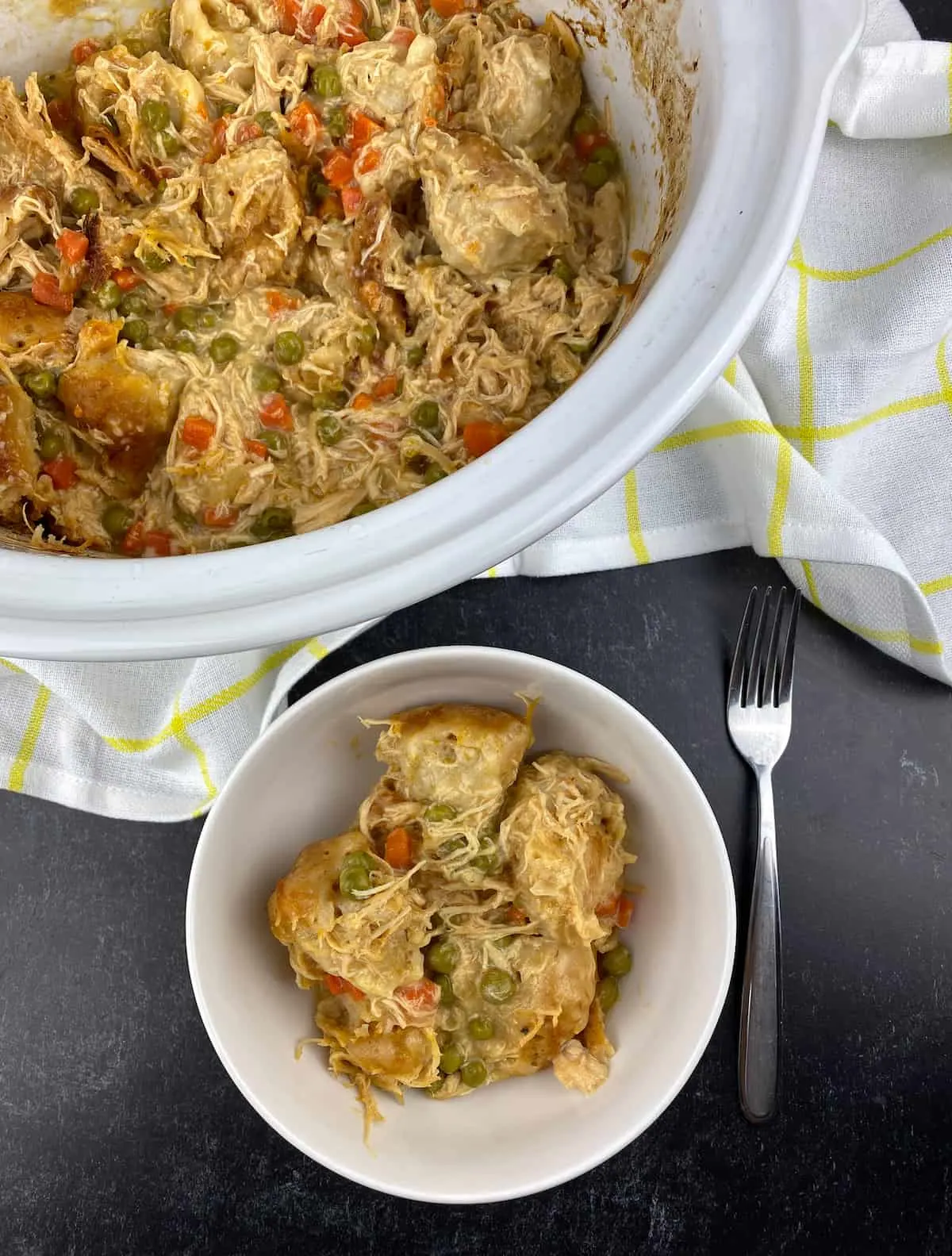 crock pot insert with bowl of chicken and dumplings made with canned biscuits