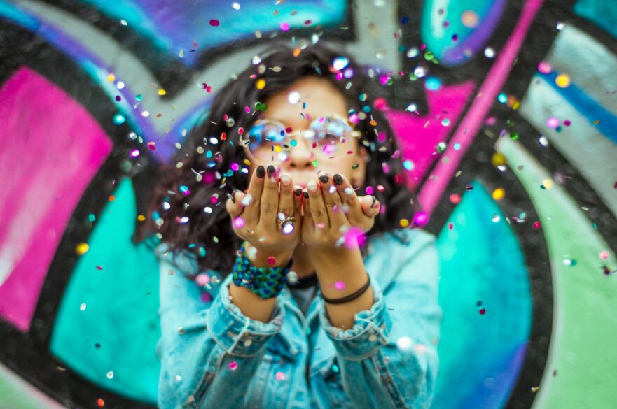 A girl blowing confetti out of her hands.