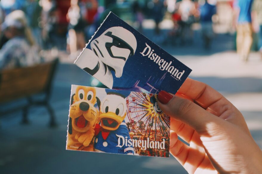 A hand holding 2 Disneyland tickets.