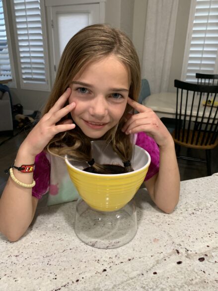 Hair ends being dyed in a bowl of the Kool-Aid mixture.