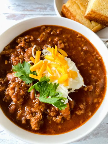 bowl of pork chili with sour cream cheese and cilantro