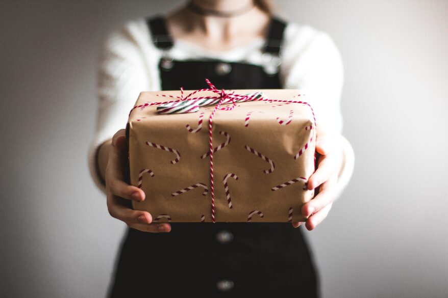 A girl holding a wrapped Christmas gift.