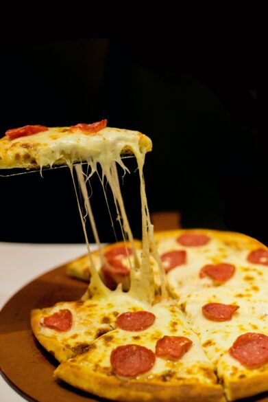 A pepperoni pizza with a slice being pulled away.