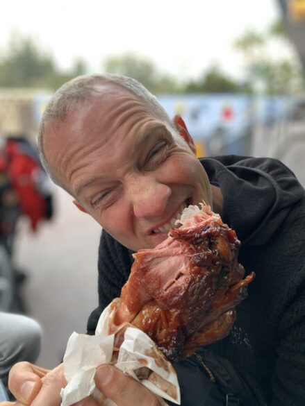 A man biting into a large turkey leg.