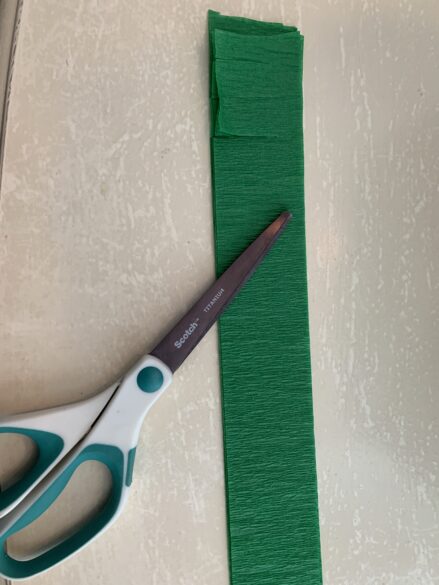 A strip of crepe paper starting to be cut.