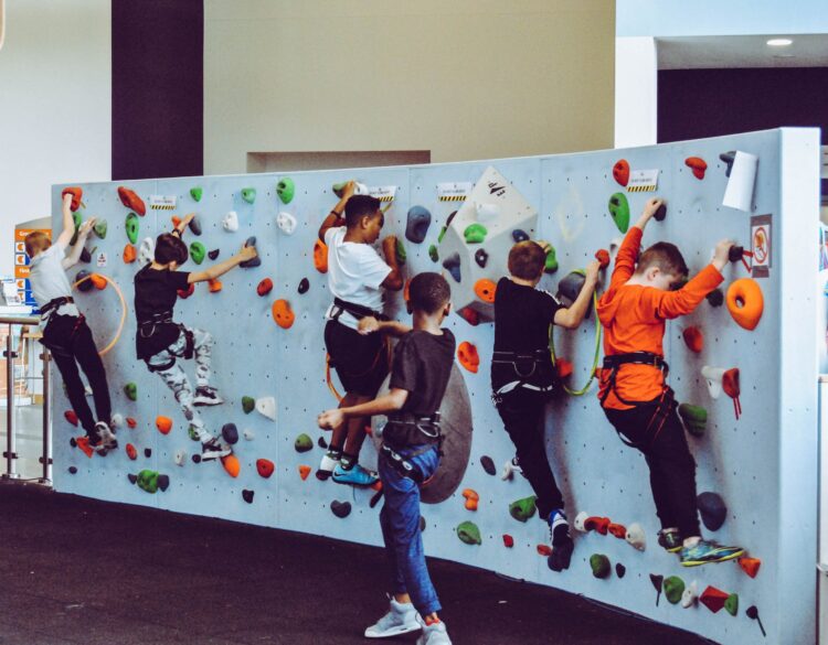 Kids climbing on a small indoor climbing wall.