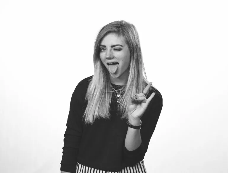 A girl sticking out her tongue, winking and making a hand sign.