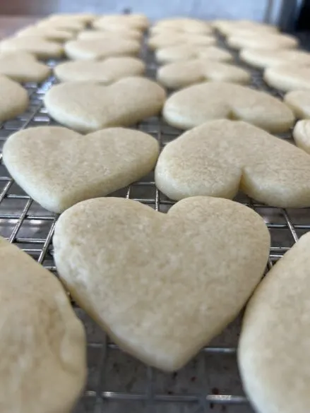 Heart shaped sugar cookies on a cooling rack.