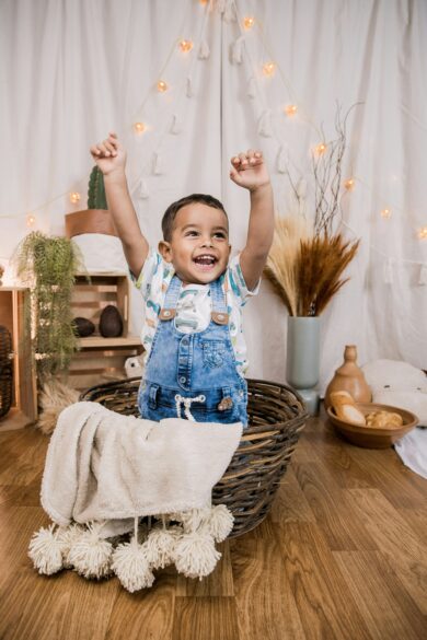 A child in a basket with his arms in the air.