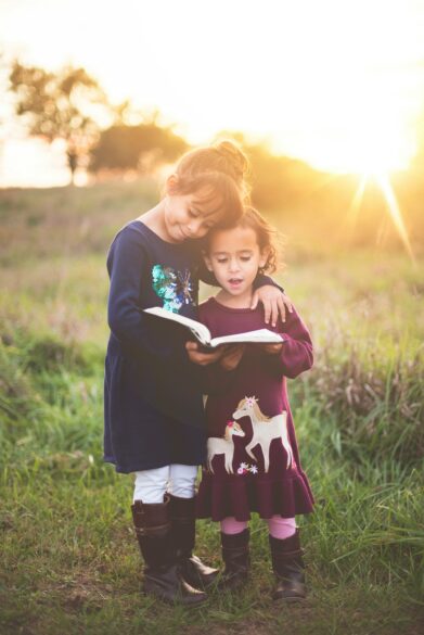 Two little girls holding a book together.