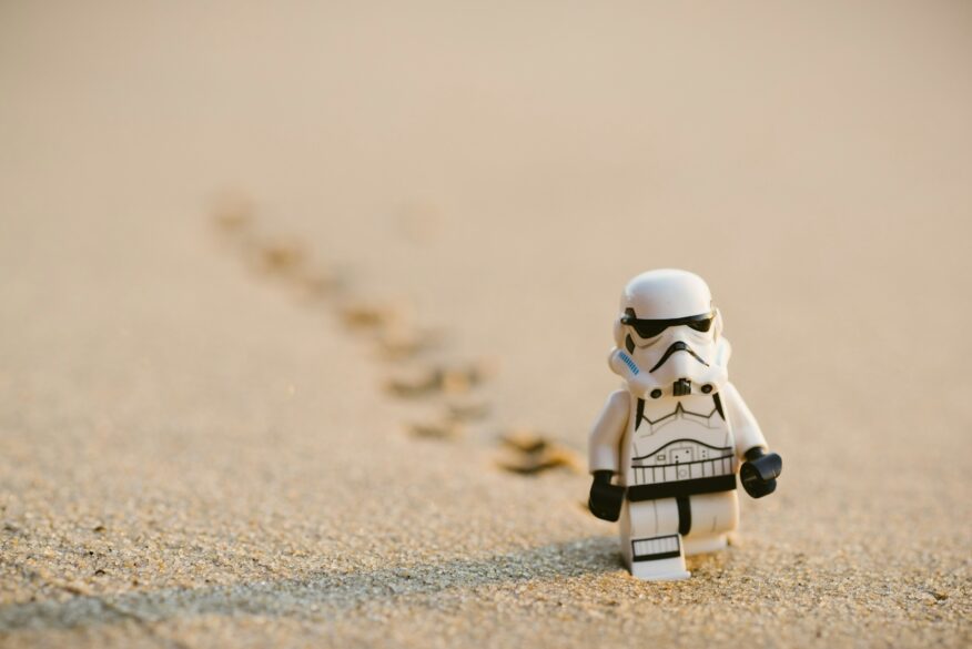 Lego storm trooper standing in the sand.