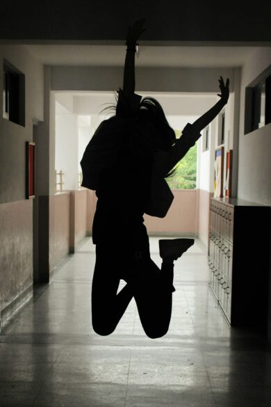 Girl jumping up in the air in the school hallway.