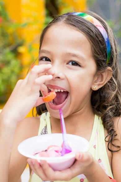 A girl eating a piece of candy while holding a bowl of ice cream. Party Ideas to Celebrate the End of School