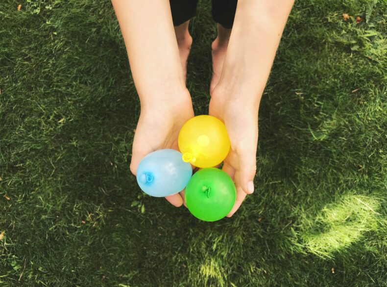 A set of hands cupping 3 water balloons.
